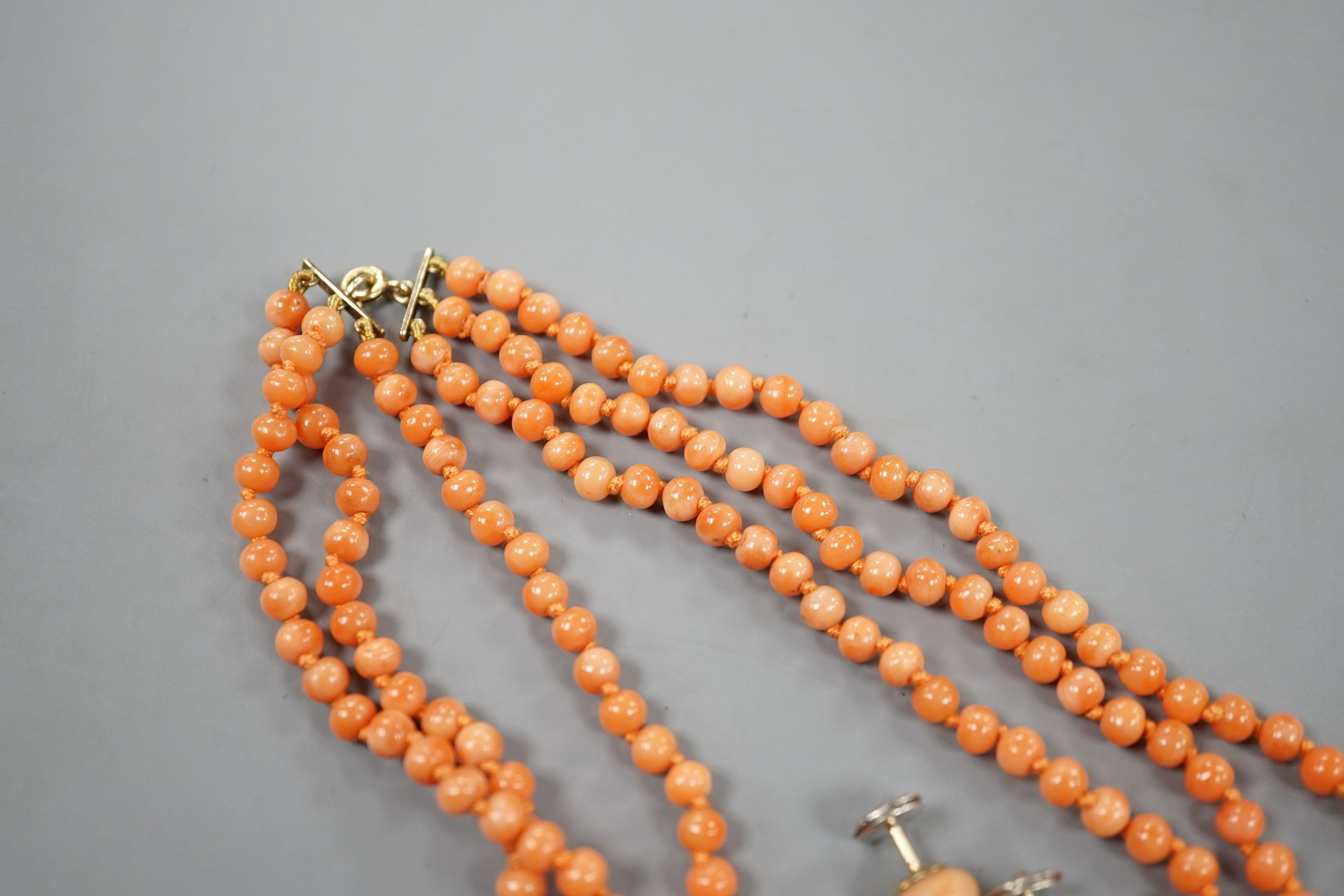 A triple strand coral bead necklace, 46cm and a pair of coral bead earrings.